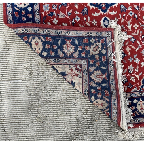 133 - A modern Persian rug decorated with foliate scrolls, on a red ground; together with another similar ... 