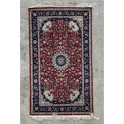 133 - A modern Persian rug decorated with foliate scrolls, on a red ground; together with another similar ... 