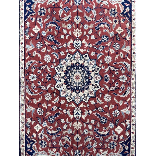 133 - A modern Persian rug decorated with foliate scrolls, on a red ground; together with another similar ... 