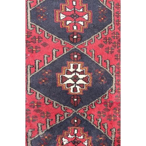 136 - A Persian Hamadan woollen hand knotted rug with three central guls within borders, 152 by 90cms.