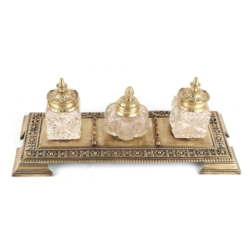 342 - A pierced brass desk stand with three cut glass inkwells, 33cms wide.