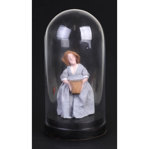 58 - A Folk Art carved wooden doll in a gingham dress, under a glass dome, 20cms high.