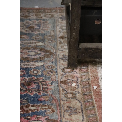 121 - A large Persian hand knotted woollen rug decorated with foliate scrolls, on a red ground, 310 by 330... 