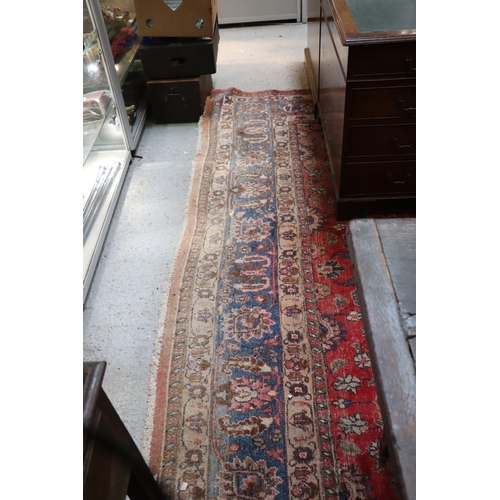 121 - A large Persian hand knotted woollen rug decorated with foliate scrolls, on a red ground, 310 by 330... 