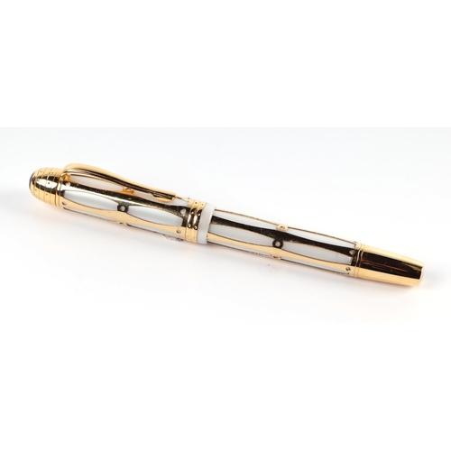 1032 - A white enamel and gilt fountain pen with iridium point nib, 14cms long.