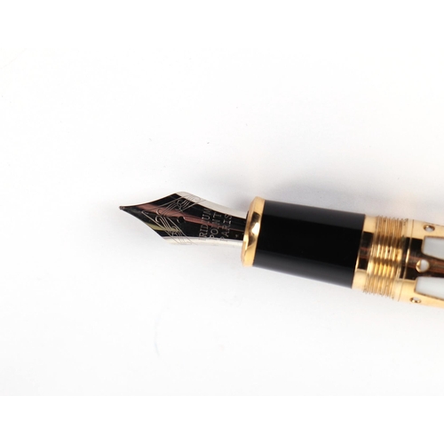 1032 - A white enamel and gilt fountain pen with iridium point nib, 14cms long.