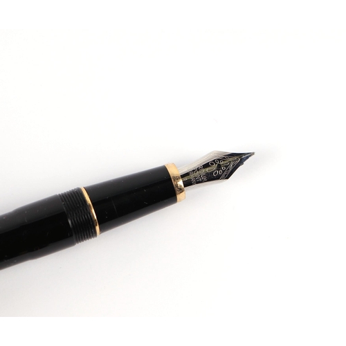 1033 - A black lacquer and gilt metal fountain pen with iridium point nib, 13cms long.