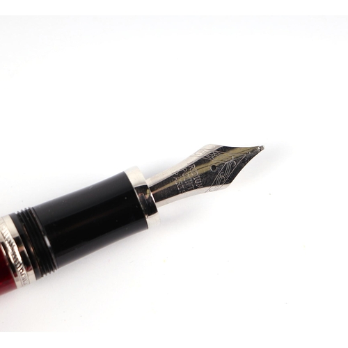 1034 - A red guilloche enamel fountain pen with iridium point nib, 15cms long.