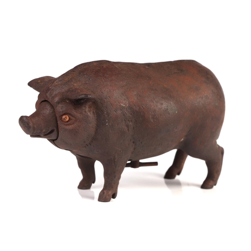 1040 - A cast iron mechanical clockwork table bell in the form of a pig with glass eyes, 14cm long