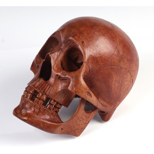 1044 - A memento mori life size carved wooden skull, 20cm long.