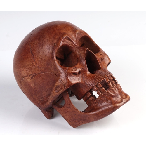 1044 - A memento mori life size carved wooden skull, 20cm long.