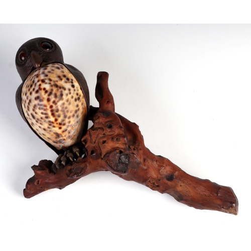 1050 - A late 19th century Cowrie shell and copper owl with glass eyes perched on a branch, possibly a wall... 