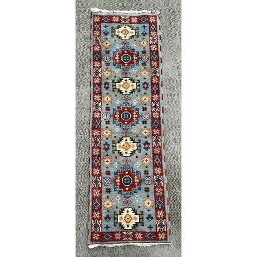 1373 - A Persian runner, having repeating geometric motifs on a blue ground within a maroon geometric borde... 