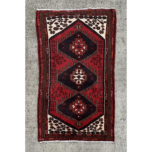 1375 - A Persian Hamadan woollen hand knotted rug with three central guls within borders, 152 by 90cms.