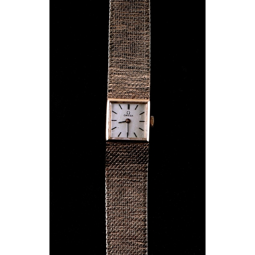 1701 - A ladies 9ct gold Omega wrist watch, the dial with hour marker batons on a textured 9ct gold strap, ... 