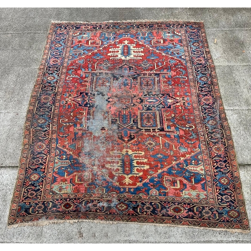 1998 - A large Persian Heriz rug with geometric design, on a rust ground, 290 by 356cms.