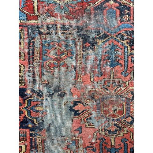 1998 - A large Persian Heriz rug with geometric design, on a rust ground, 290 by 356cms.