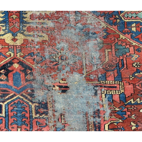 1998 - A large Persian Heriz rug with geometric design, on a rust ground, 290 by 356cms.