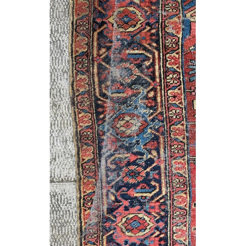 1998 - A large Persian Heriz rug with geometric design, on a rust ground, 290 by 356cms.