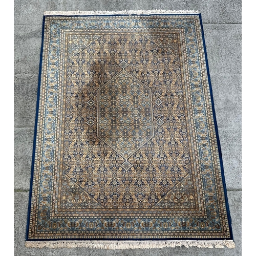 1999 - A Keshan rug with repeated geometric design on a beige ground. 250 by 344cm