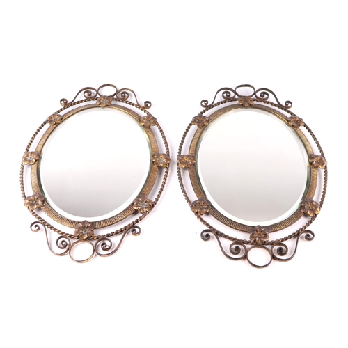 2006 - A pair of Regency style gilt brass oval wall mirrors, the frames with flowers to the rim and having ... 