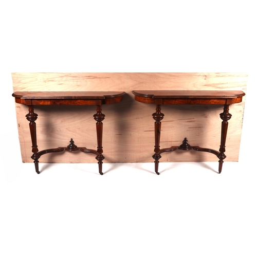 2015 - A pair of burr walnut console tables, the crossbanded shaped top above turned supports joined by a s... 