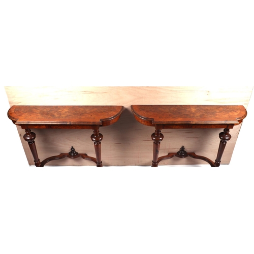 2015 - A pair of burr walnut console tables, the crossbanded shaped top above turned supports joined by a s... 