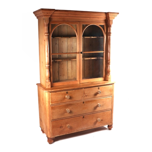 2064 - A pine bookcase on cupboard, the upper section with a moulded cornice above twin glazed doors enclos... 