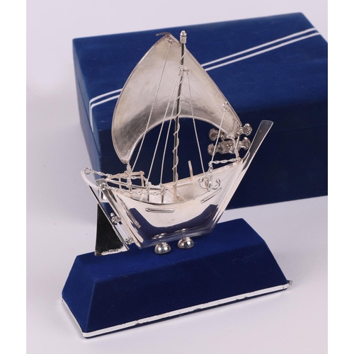 381 - A silver model of a boat on a stand, boxed. boat 13cm long