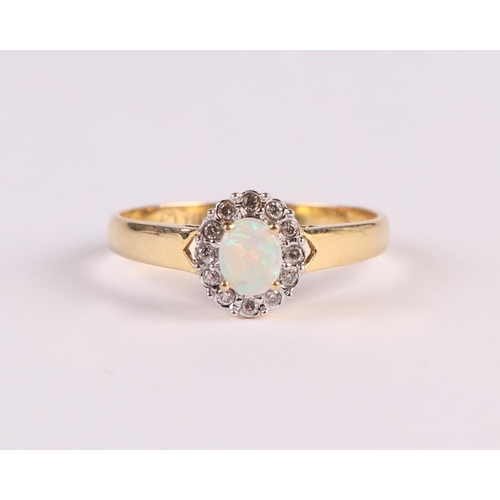 447 - An 18ct gold ring set with a central oval opal surrounded by diamonds, approx UK size 'N', 2.3g.