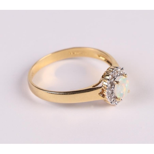 447 - An 18ct gold ring set with a central oval opal surrounded by diamonds, approx UK size 'N', 2.3g.