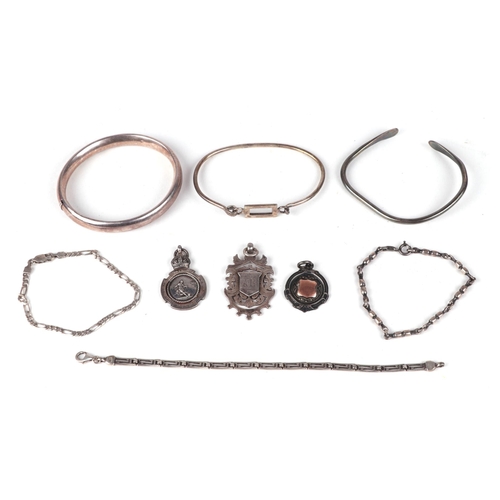 453 - A group of silver bracelets and bangles together with three silver pocket watch fobs, 86g.