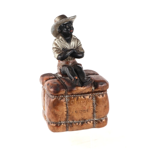 62 - A 19th century French terracotta tobacco box and cover in the form of a seated black boy on a bale o... 