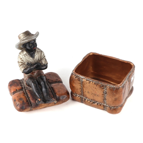 62 - A 19th century French terracotta tobacco box and cover in the form of a seated black boy on a bale o... 