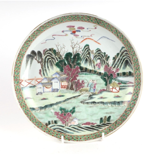 656 - A Chinese famille vert shallow bowl decorated with figures in a landscape, 26cms diameter.