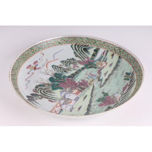 656 - A Chinese famille vert shallow bowl decorated with figures in a landscape, 26cms diameter.