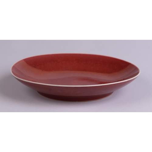 670 - A Chinese red glazed monochrome shallow saucer dish, 17cms diameter.