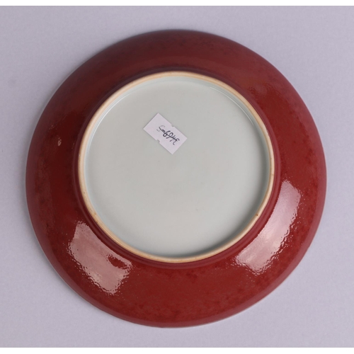 670 - A Chinese red glazed monochrome shallow saucer dish, 17cms diameter.