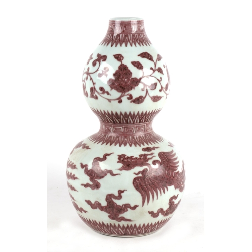 672 - A Chinese red and white double gourd vase decorated with phoenix amongst clouds, 35cms high.