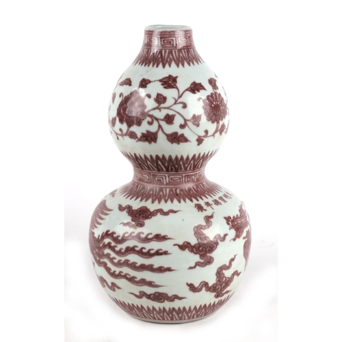 672 - A Chinese red and white double gourd vase decorated with phoenix amongst clouds, 35cms high.