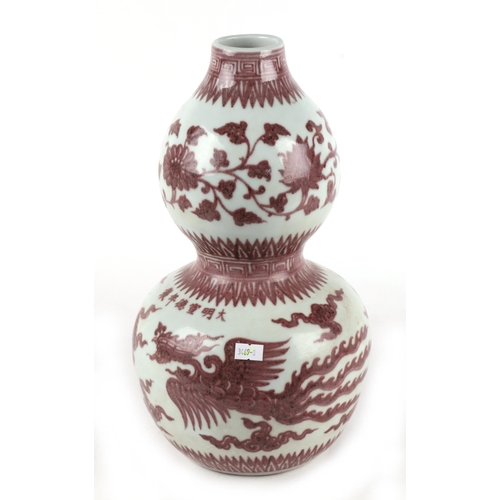 672 - A Chinese red and white double gourd vase decorated with phoenix amongst clouds, 35cms high.