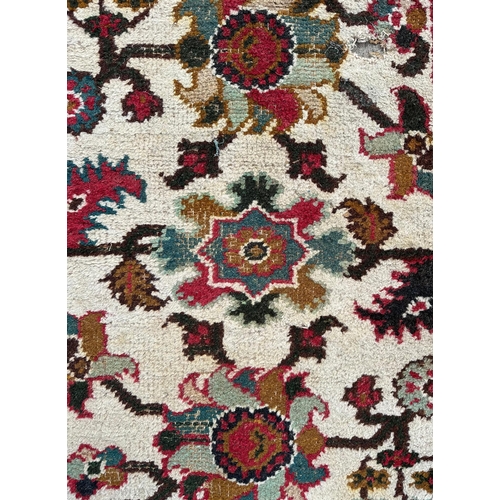 733 - A Caucasian rug having a repeating floral motifs on a cream ground within a red and floral border, 1... 