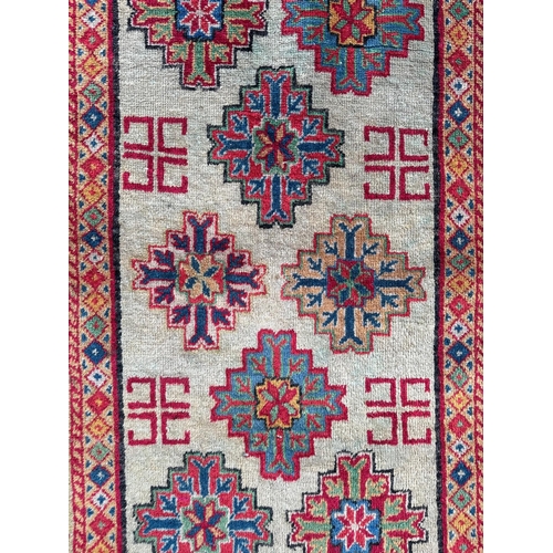 734 - A Persian rug, with repeating geometric motifs on a red ground within a blue and yellow geometric bo... 