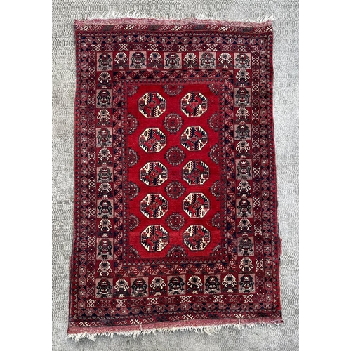 736 - A Persian rug with repeated medallion design, on a red ground, 133 by 207cms.