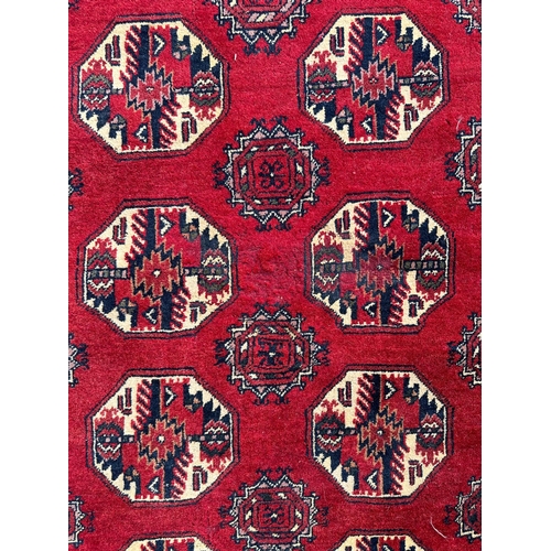 736 - A Persian rug with repeated medallion design, on a red ground, 133 by 207cms.