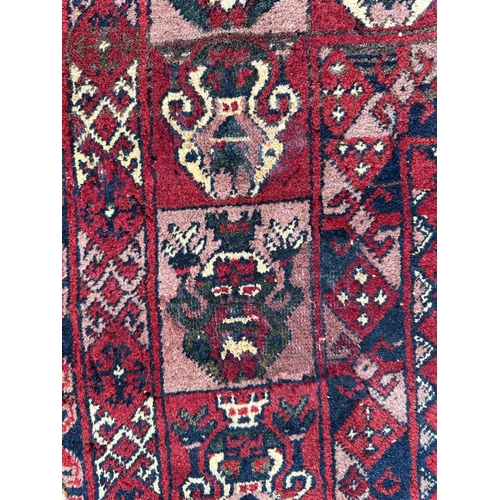 736 - A Persian rug with repeated medallion design, on a red ground, 133 by 207cms.