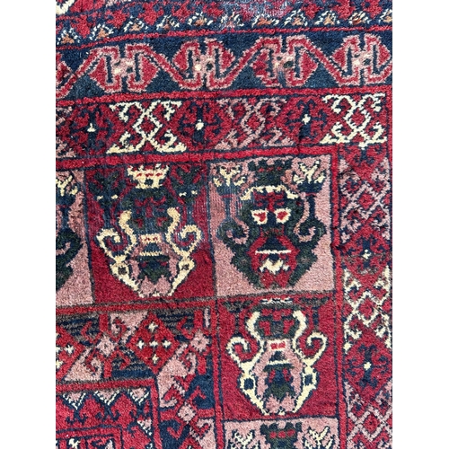 736 - A Persian rug with repeated medallion design, on a red ground, 133 by 207cms.