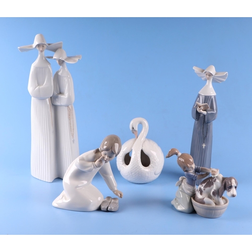 76 - A group of Lladro figures to include nuns, small girls and a swan, the largest 32cms high (5).