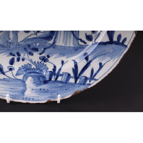 771 - An early 18th century English Delft shallow dish decorated with a chinoiserie scene depicting a lady... 