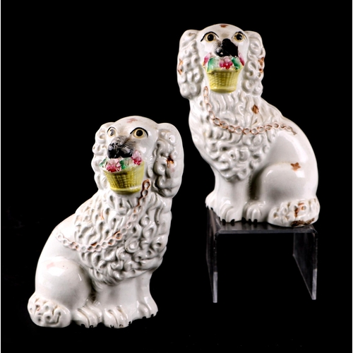 773 - A pair of 19th century Staffordshire figures depicting dogs holding baskets of flowers in their mout... 